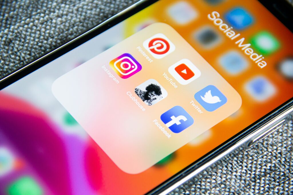 Close-up of smartphone displaying social media apps including Instagram, Facebook, YouTube, Twitter, Pinterest, and Clubhouse, representing online marketing and digital communication.